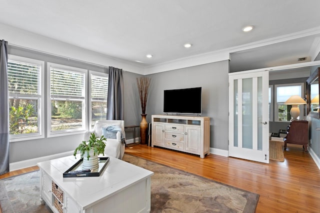 living room featuring light hardwood / wood-style floors, crown molding, and a wealth of natural light