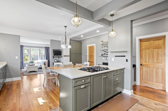 kitchen with light wood-type flooring, pendant lighting, stainless steel gas cooktop, and crown molding