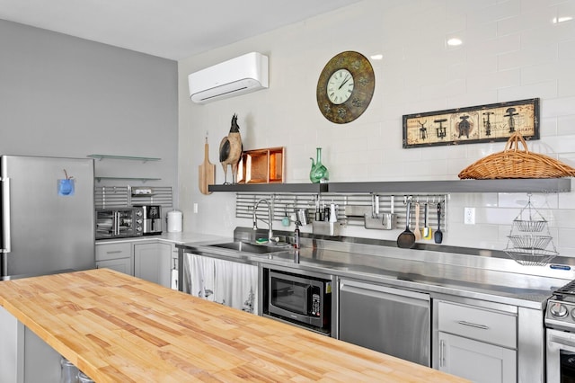 kitchen featuring sink, gray cabinetry, butcher block countertops, stainless steel appliances, and a wall mounted AC