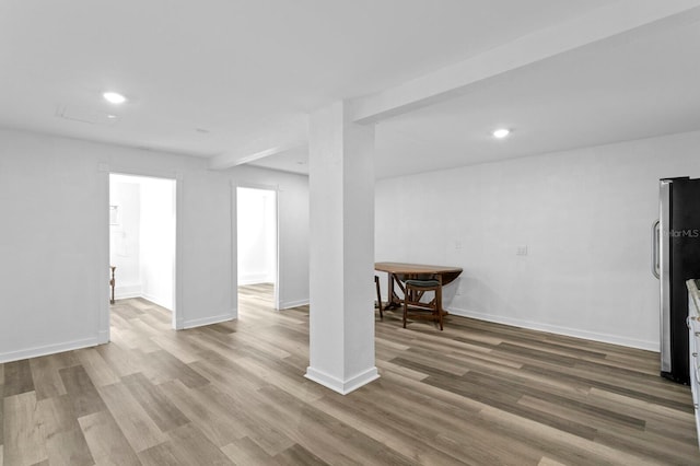 basement with hardwood / wood-style flooring and stainless steel fridge