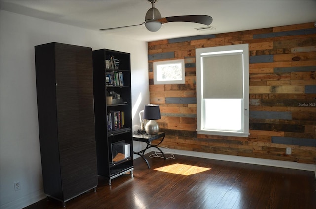 office area with ceiling fan, wood walls, and dark hardwood / wood-style floors