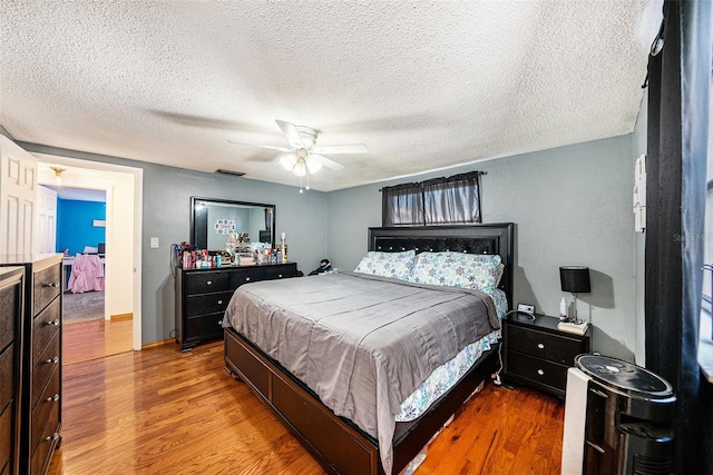 bedroom with hardwood / wood-style flooring, a textured ceiling, and ceiling fan