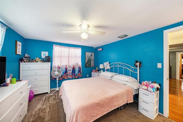 carpeted bedroom featuring ceiling fan and a textured ceiling