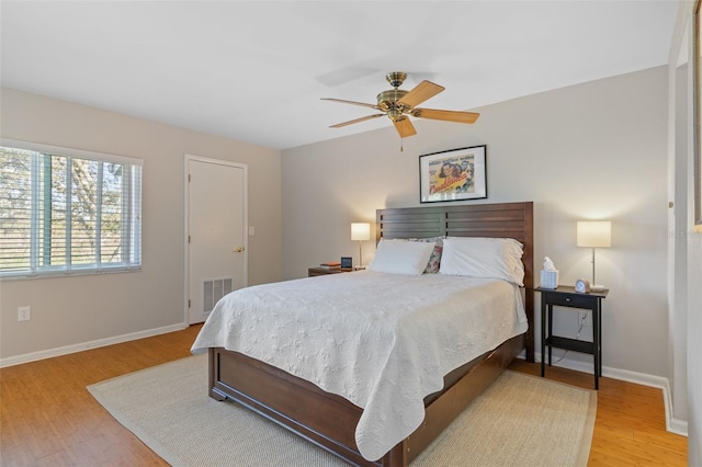 bedroom featuring light wood finished floors, baseboards, visible vents, and a ceiling fan