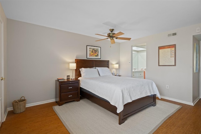 bedroom featuring baseboards, visible vents, ceiling fan, wood finished floors, and ensuite bathroom