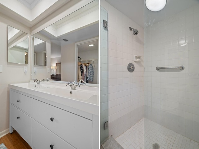 full bath featuring a sink, visible vents, a shower stall, double vanity, and a walk in closet