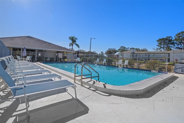 community pool with a patio and fence