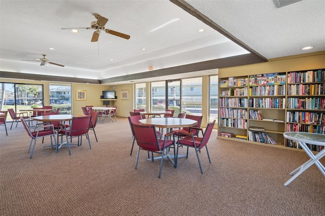 dining space with a textured ceiling, carpet floors, a tray ceiling, and recessed lighting