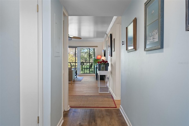 hall featuring ornamental molding, baseboards, and wood finished floors