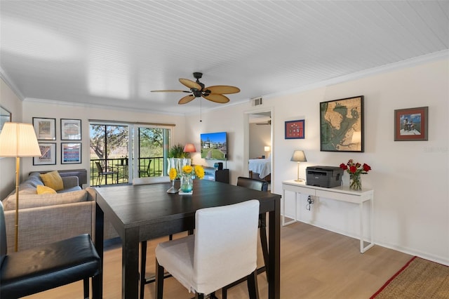 dining space with ornamental molding, visible vents, ceiling fan, and wood finished floors