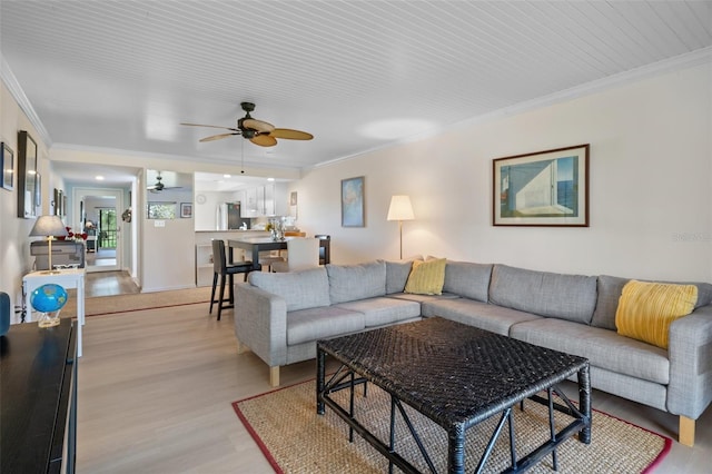 living room featuring ceiling fan, light wood-style floors, and crown molding