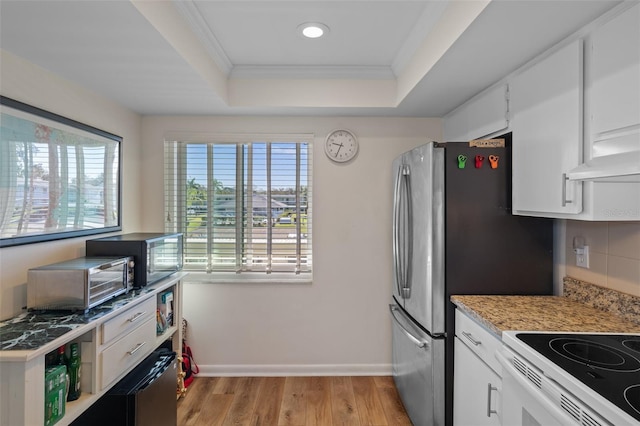 kitchen featuring baseboards, white cabinets, light wood-style flooring, a tray ceiling, and crown molding