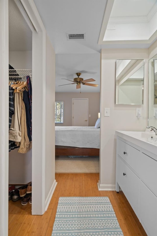 ensuite bathroom with vanity, visible vents, connected bathroom, and wood finished floors