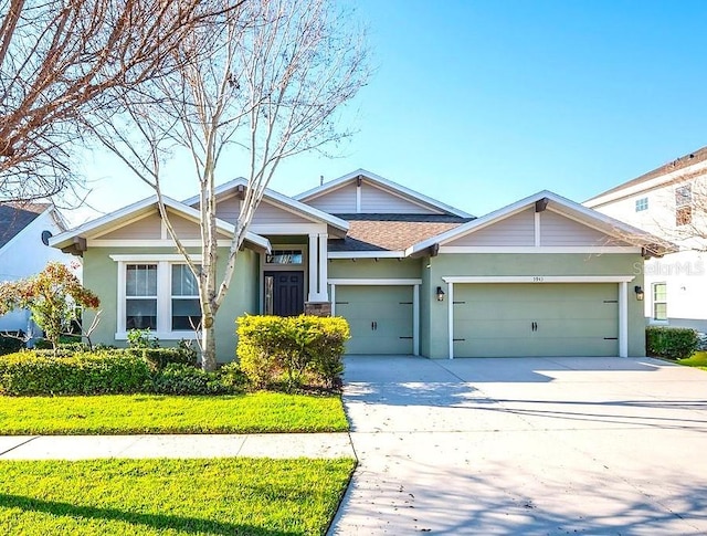 craftsman inspired home featuring driveway, roof with shingles, an attached garage, a front lawn, and stucco siding