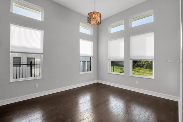 empty room with dark wood-style flooring and baseboards