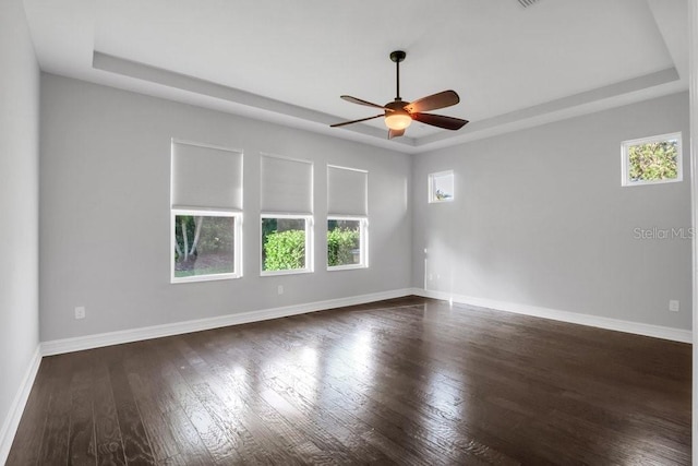 spare room with dark wood-style floors, a raised ceiling, and baseboards