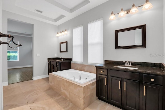 full bathroom featuring a garden tub, baseboards, two vanities, and a sink