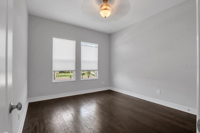 unfurnished room featuring dark wood-type flooring and baseboards