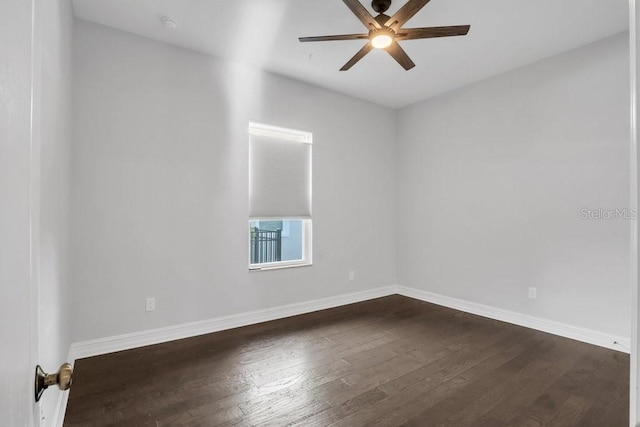 spare room featuring a ceiling fan, dark wood-style flooring, and baseboards