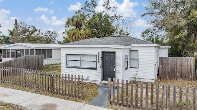 view of front of house featuring a shingled roof and a fenced front yard