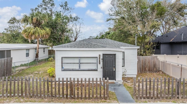 view of front facade with a fenced backyard and a shingled roof