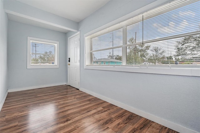 unfurnished room featuring dark wood-type flooring and baseboards