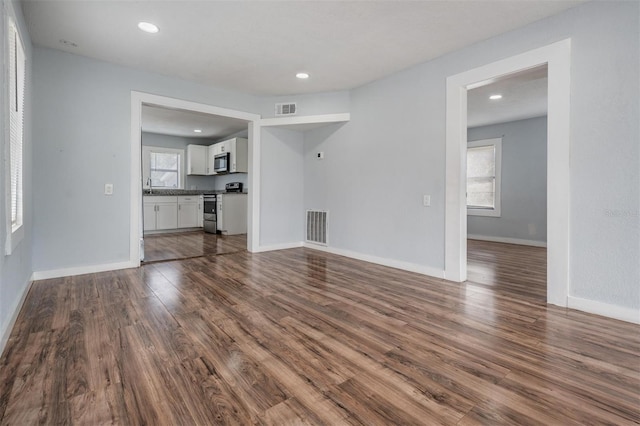 unfurnished living room featuring dark wood-type flooring, recessed lighting, visible vents, and baseboards