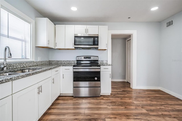 kitchen featuring visible vents, appliances with stainless steel finishes, stone counters, white cabinetry, and a sink