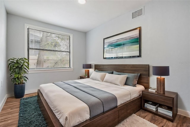 bedroom featuring visible vents, baseboards, and wood finished floors