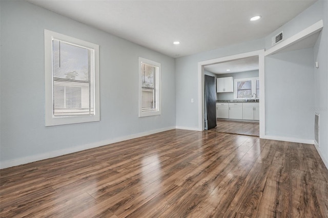 unfurnished living room featuring recessed lighting, wood finished floors, visible vents, and baseboards