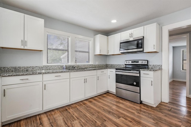 kitchen featuring light stone countertops, white cabinetry, stainless steel appliances, and a sink