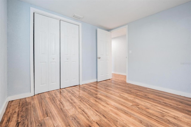 unfurnished bedroom with a closet, visible vents, light wood-style flooring, and baseboards