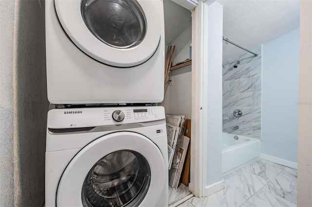 laundry room with marble finish floor, stacked washer / dryer, a textured ceiling, laundry area, and baseboards