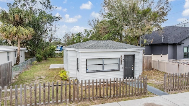 view of front of property with a shingled roof and a fenced front yard