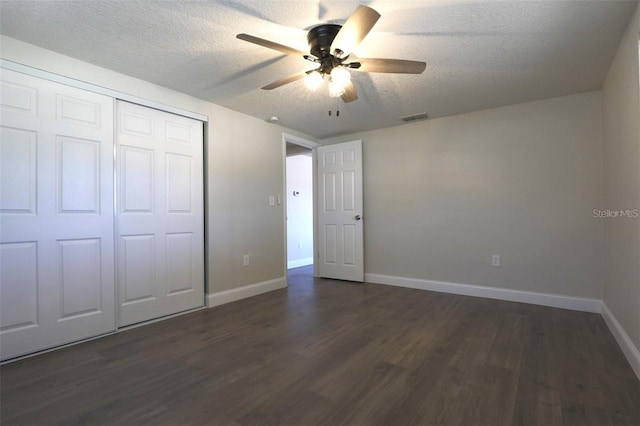 unfurnished bedroom with ceiling fan, dark wood-type flooring, a textured ceiling, and a closet