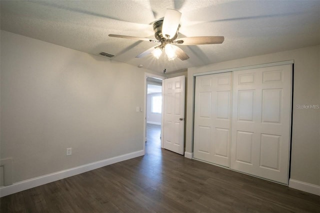 unfurnished bedroom featuring ceiling fan, dark wood-type flooring, a textured ceiling, and a closet