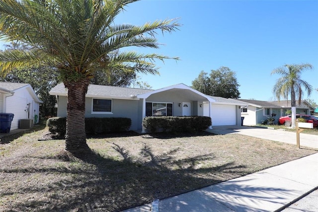 ranch-style home featuring central AC unit and a garage