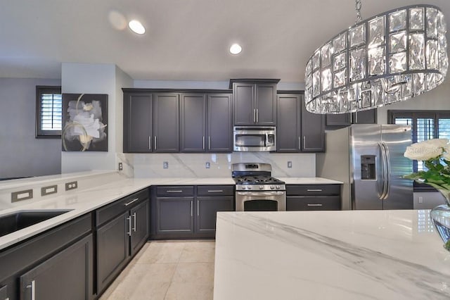 kitchen with appliances with stainless steel finishes, light stone counters, decorative backsplash, and light tile patterned floors