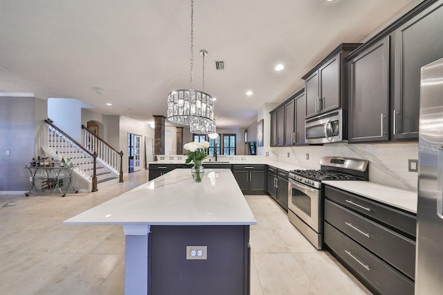 kitchen featuring appliances with stainless steel finishes, backsplash, a center island, decorative light fixtures, and kitchen peninsula