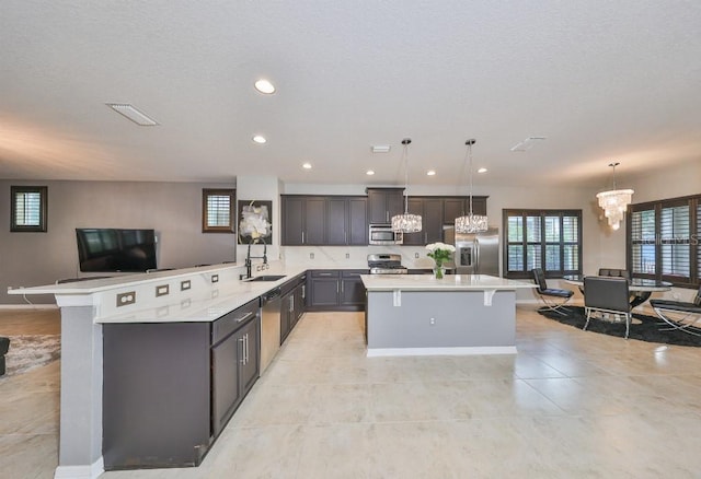 kitchen with sink, hanging light fixtures, an inviting chandelier, and stainless steel appliances