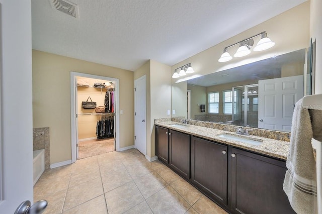 bathroom with a textured ceiling, vanity, tile patterned flooring, and independent shower and bath