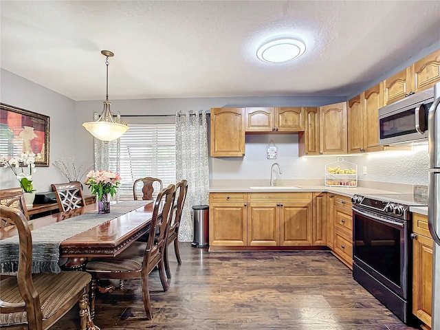 kitchen featuring sink, appliances with stainless steel finishes, hanging light fixtures, dark hardwood / wood-style floors, and a textured ceiling