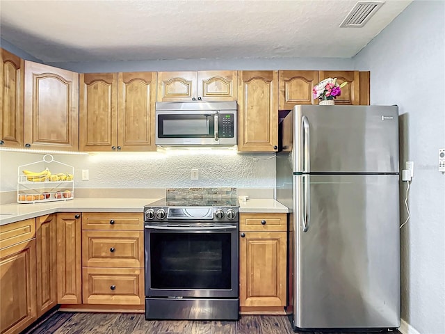 kitchen featuring dark wood-type flooring, stainless steel appliances, and a textured ceiling