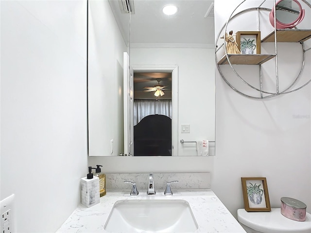 bathroom with crown molding, ceiling fan, vanity, and toilet