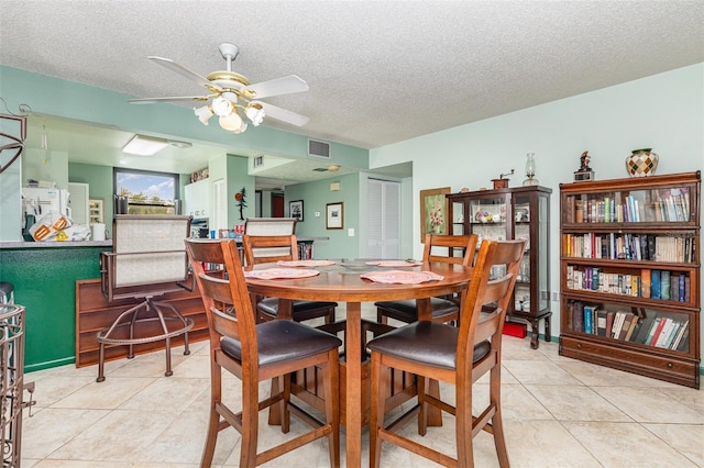 tiled dining space with ceiling fan and a textured ceiling