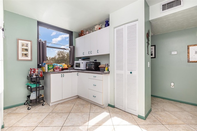 127 Tidewater Dr Unit 127, Bradenton, FL 34210 - kitchen featuring light tile patterned floors, dark countertops, white cabinetry, visible vents, and white microwave
