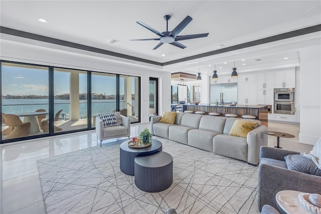 living room with ceiling fan and a water view