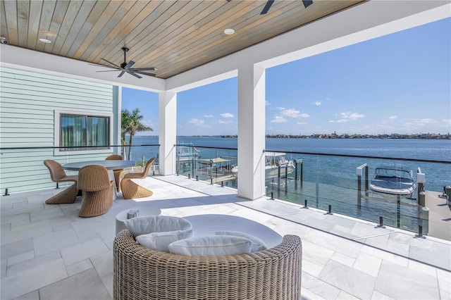 view of patio with a water view, ceiling fan, and a boat dock