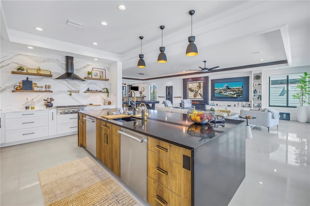 kitchen featuring white cabinetry, hanging light fixtures, sink, a tray ceiling, and wall chimney exhaust hood