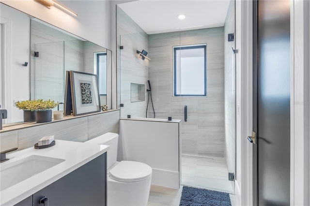 bathroom featuring tile walls, toilet, a shower with door, and vanity